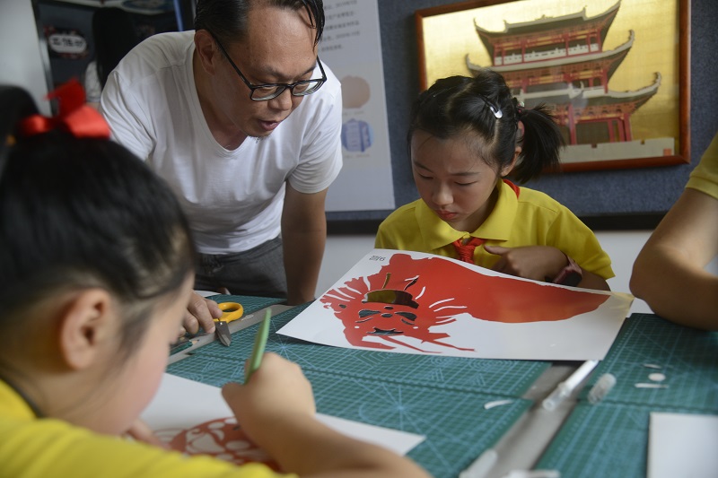 民间艺人张寿疆在认真指导学生们制作纸雕作品