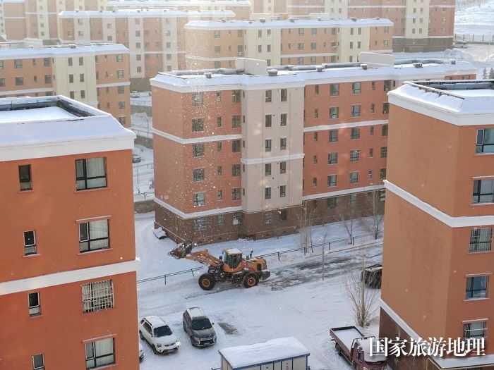 正在阿勒泰地区阿勒泰市恰秀南苑小区清理积雪的铲车。