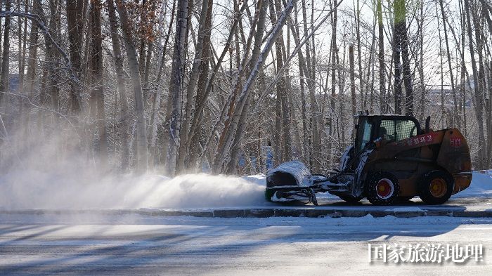 正在阿勒泰市一人行道清理积雪的小型机械设备。