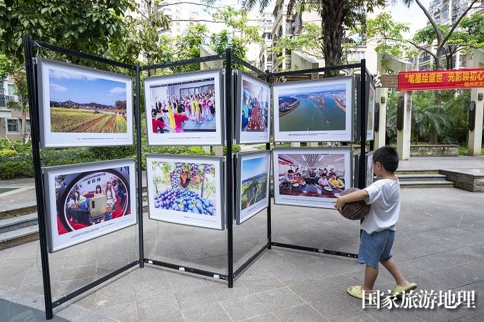 9、2024年7月20日，居民在广西梧州市万秀区蓝天社区蓝天港湾小区观看摄影展。（何华文）